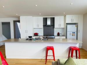 a kitchen with white cabinets and red stools at Annies View in Emu Bay