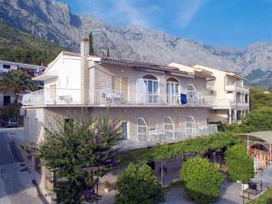 a large house with a balcony and mountains in the background at B&B villa IVONA in Baška Voda