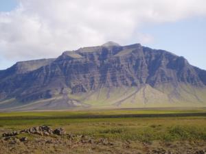 a large mountain in the middle of a field at Eldborg Cabins and Guesthouse in Kolbeinsstaðir +35 photos