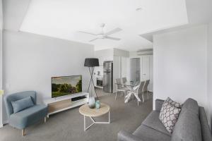 a living room with a couch and a tv at Direct Collective - Sea Breeze Mooloolaba in Mooloolaba