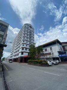 ein hohes weißes Gebäude in einer Stadtstraße mit Autos in der Unterkunft Kawan Hotel in Sibu