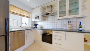 a kitchen with white cabinets and a sink at Charmante Wohnung direkt am Meer, kostenloses WLAN in Puerto de Mogán