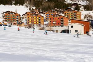 迪森蒂斯的住宿－Reka-Feriendorf Disentis，一群人沿着雪覆盖的斜坡滑雪