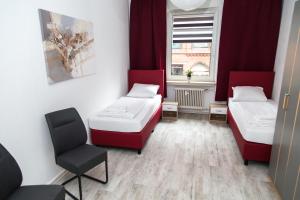 a room with two beds and a chair in it at Othman Appartements Falkenstraße 26 3OG L in Hannover