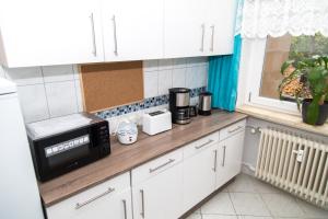 eine Küche mit weißen Schränken und einer Mikrowelle auf der Theke in der Unterkunft Othman Appartements Falkenstraße 26 3OG L in Hannover