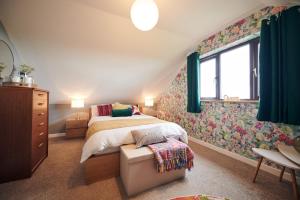 1 dormitorio con cama y pared de flores en Maes Y Mel- A Couples, Pet Friendly, Rural Romantic Getaway with countryside views en Gelliwen