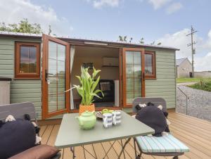 a tiny house with a table and chairs on a deck at Llety'r Bugail 2 in Caernarfon