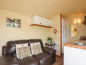 a living room with a leather couch and a kitchen at Llety'r Bugail 2 in Caernarfon