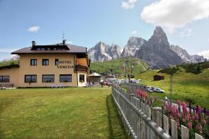 a building with a fence and mountains in the background at Albergo Venezia in Passo Rolle