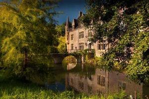 un edificio junto a un río con un puente en Van der Valk Hotel Kasteel Terworm, en Heerlen