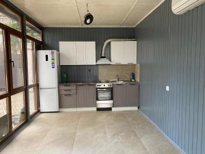 a kitchen with a white refrigerator and gray cabinets at Отель Гудоу in Gudauta