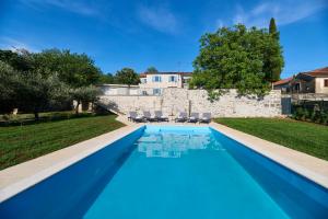 a blue swimming pool in front of a house at Holiday home Casa dei nonni with bicycles included in Oprtalj