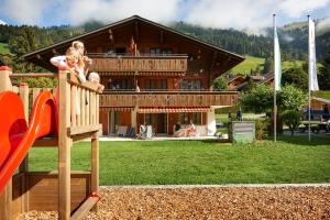 a woman and a child on a slide in front of a building at Reka-Ferienanlage Rougemont in Rougemont