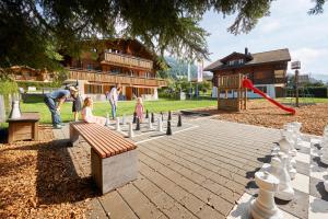 um grupo de pessoas jogando xadrez em um playground em Reka-Ferienanlage Rougemont em Rougemont