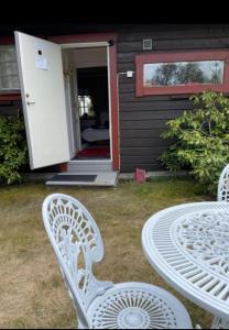 two white chairs and a table in front of a house at Cosy non smoking Cabin close to beach,Alnö in Sundsvall