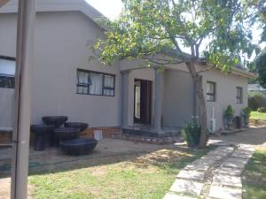 een wit huis met een boom in de tuin bij Genie's Nest Ooie 1 in Pretoria