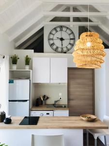 a kitchen with a table and a clock on the wall at STUDIO COSY LES FRANGIPANNIERS in Oyster Pond