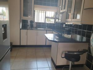 cocina con armarios blancos y encimera negra en Genie's Nest Ooie 1 en Pretoria
