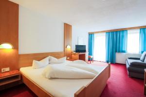 sypialnia z dużym białym łóżkiem i kanapą w obiekcie Hotel Tia Monte w mieście Kaunertal