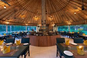 een restaurant met tafels en stoelen en een groot plafond bij Click Resort Corbett Tiger Den in Rāmnagar