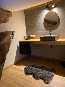 y baño con lavabo, espejo y alfombra. en Le Petit Bleu Chambre d'hôtes, en Bourg-de-Visa