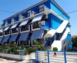 un edificio blu e bianco con tende da sole bianche di Hotel Asimina Laganas a Laganas