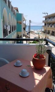 un tavolo con tazze e piattini su un balcone con spiaggia di Hotel Asimina Laganas a Laganas
