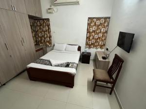 a small bedroom with a bed and a chair at Avuraa Hospitality India in Chennai