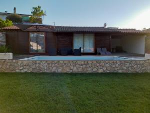 a house with a stone wall and a swimming pool at Leiria Village casa bungalow in Leiria