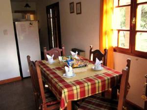 mesa de comedor con mantel rojo y amarillo en Cabañas Oma Lissi, en Merlo
