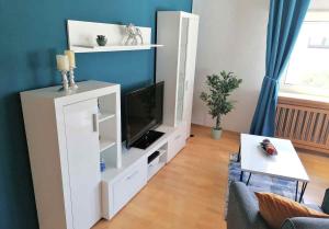 a living room with a white entertainment center with a television at 3 room Apartment in Bürstadt