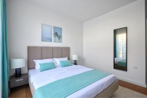 a white bedroom with a large bed with blue pillows at The luxury flat in Ahtopol