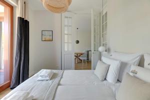 a white bedroom with a large bed with white pillows at Downtown Apartments Gdynia Seaside Nowe Orłowo in Gdynia