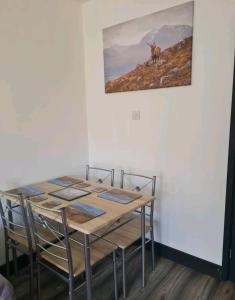 a table with chairs and a picture of a deer on the wall at Charming 1-Bed Apartment in Peebles in Peebles