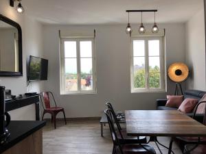 a living room with a table and two windows at Le Logis de Virginie in Rochefort