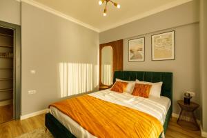 Schlafzimmer mit einem großen Bett mit orangefarbener und weißer Bettwäsche in der Unterkunft Lago Apartment Mamaia Butoaie in Mamaia