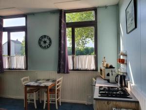 une cuisine avec une table et une horloge murale dans l'établissement Camping des 2 Rives- Chambres, à Étang-sur-Arroux