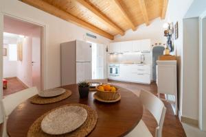 eine Küche und ein Esszimmer mit einem Holztisch und Stühlen in der Unterkunft Ortigia Colourful Apartment in Syrakus