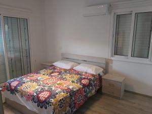 a bedroom with a bed with a colorful comforter and two windows at The Anemoni 5 Villa in Protaras +10 photos