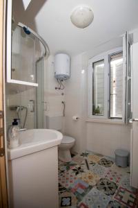 Baño blanco con lavabo y aseo en Beachfront Studio AndriNa, en Vis