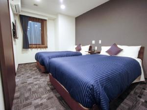 a hotel room with two beds and a window at HOTEL LiVEMAX Nagoya Sakae East in Nagoya