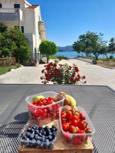 una mesa con dos recipientes de plástico de frutas y hortalizas en Apartmani Urlic, en Sreser