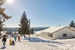 um grupo de pessoas andando na neve perto de uma cabana em Reka-Feriendorf Montfaucon em Montfaucon
