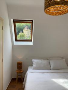 a bedroom with a white bed and a window at Les Courtines - Appartement de caractère à la Roque-Gageac - Les Cerisiers in La Roque-Gageac
