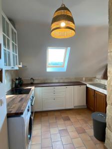 a kitchen with white cabinets and a washer and a window at Les Courtines - Appartement de caractère à la Roque-Gageac - Les Cerisiers in La Roque-Gageac
