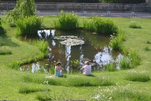 zwei Frauen sitzen im Gras vor einem Teich in der Unterkunft Hotel Diana in San Zeno di Montagna