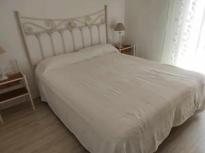 a white bed in a bedroom with a window at Casa La Gaviota en el centro de Zahara in Zahara de los Atunes