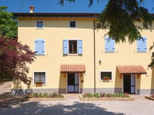 Casa amarilla con puertas y ventanas blancas en Cason degli Ulivi, en Rivoli Veronese