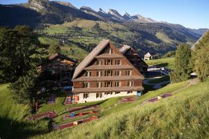 a large building on a hill with mountains in the background at Reka-Feriendorf Wildhaus in Wildhaus