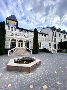 a large white building with a fountain in front of it at Гетьман Готель & SPA in Chortkiv